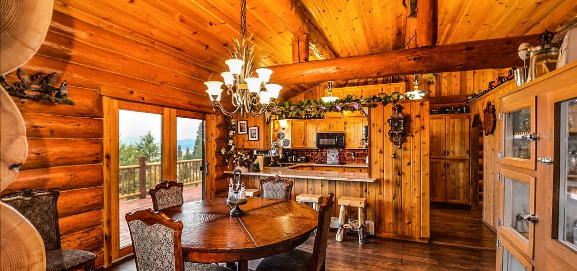 Log cabin interior with dining area and kitchen, showcasing stained wood siding AZ Painting Ltd.