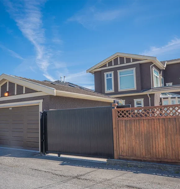 Residential stucco waterproofing on a brown house with a garage and wooden fence. AZ Painting Ltd.